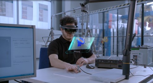 Bildunterschrift: Der Wissenschaftler Ali Movahed bei der Prüfung eines Bauteils auf Fehler im Materialinneren mit einer Augmented Reality-Brille (AR). 